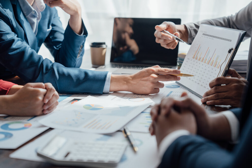 Accounting fund managers discuss investment strategies, analyze documents, and review charts during a meeting.